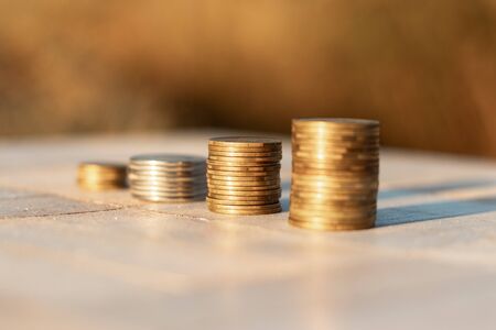 Stacks of coins laying down on the table on the beautiful sunset background, economy growth and strategy conceptの写真素材