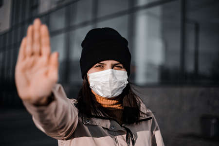 Young woman dramatic portrait showing stop sign with her hand against coronavirus. Say no to Covid-19 Chineese virus become a pandemia. Quarantine and isolation to prevent nCov2019の写真素材