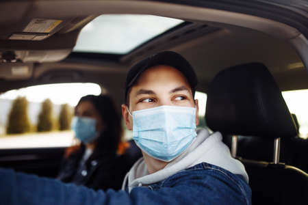 Man driving a car wearing sterile medical mask. Taxi driver with a passanger stuck in a traffic jam...