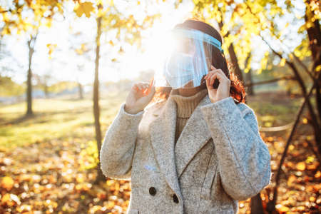 Young woman wearing a face shield to protect from coronavirus desease stands in the park during...