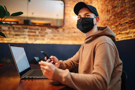 Shopping and online payment using cellphone, laptop and credit card. Man wearing mask during...