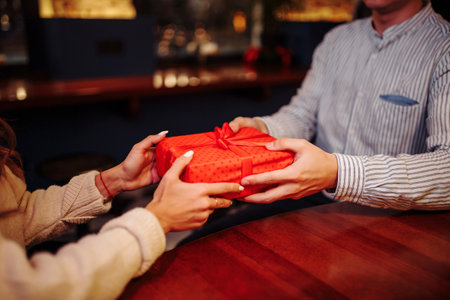 A young loving couple celebrating Valentine's Day 
by exchanging gifts in the restaurant.の写真素材