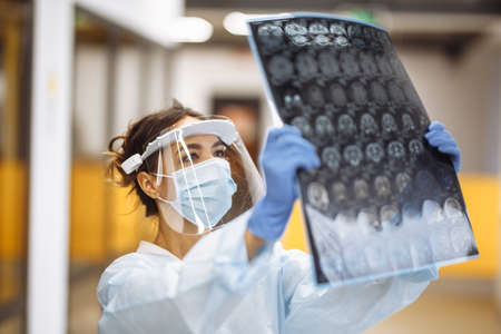 Woman doctor is checking brain MRI x-ray image of the patient at the hospital. Female medical worker...