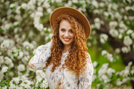Portrait of a girl smiling and being happy on a bright sunny spring day. Young woman with curly hair...