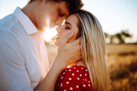 Man and woman at sunset in a wheat field. A loving couple at sunset. Portrait of a young girl and a guyの写真素材