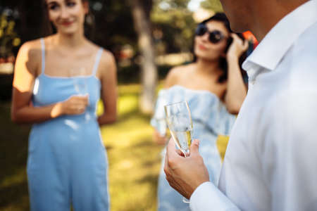 A man with a glass of champagne in his hands against the background of a company of celebrating...