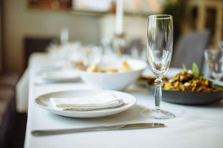 Ceramic tableware and luxury plate setting on table. Champagne glass, plate and napkin on the table...