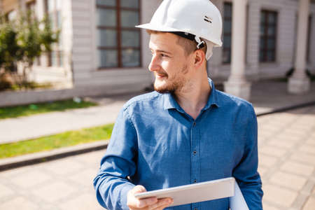 An engineer or an architect in a helmet with a tablet in his hands. Monitoring the progress of...