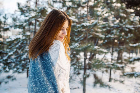 Portrait of a red-haired girl in mittens against the background of a winter park. Beautiful woman is enjoying nature on a snowy dayの写真素材