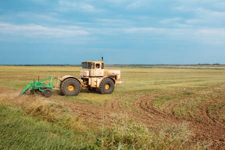 Tractor cultivating field. Plowing fields. Preparing land for sowing. Rich harvest conceptの写真素材
