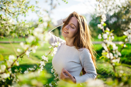 Portrait of a beautiful young woman posing in a spring blooming park. The concept of spring, love, happiness, femininityの写真素材