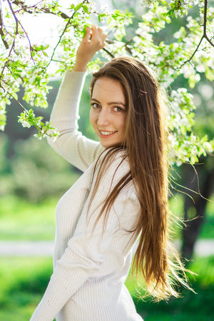 A charming young woman graces a springtime park with her presence, symbolizing the themes of renewal, love, happiness, and femininityの写真素材
