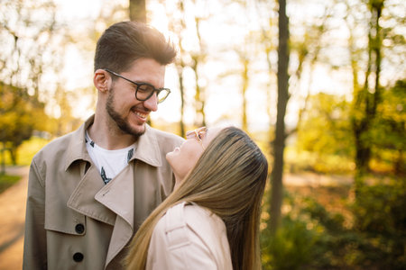 A young couple spends time happily in a spring garden at sunset. Husband and wife enjoying a walk in the park. Concept of joy, love and familyの写真素材