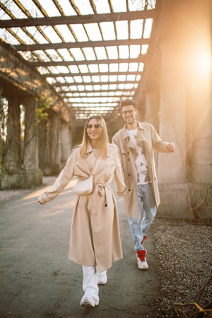 Stylish happy couple walking in the park. A woman and a man enjoy time with each other on a spring sunny day at sunset. Springtimeの写真素材
