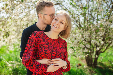 Happy couple hugging and laughing smiling with teeth on a sunny spring day. Floral landscape and nature conceptの写真素材
