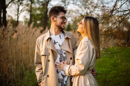 Portrait of a young man and woman looking at each other with love. Beautiful couple in a forest garden at sunset in springの写真素材