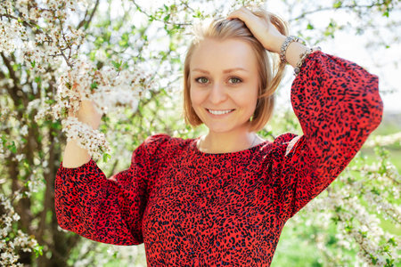 Portrait of a happy young woman smiling with teeth in a blooming garden park. Spring timeの写真素材
