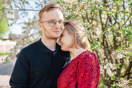 Portrait of a young happy couple. A woman and a man are hugging against the backdrop of a beautiful flowering tree. The concept of love and unity with nature. Springtimeの写真素材