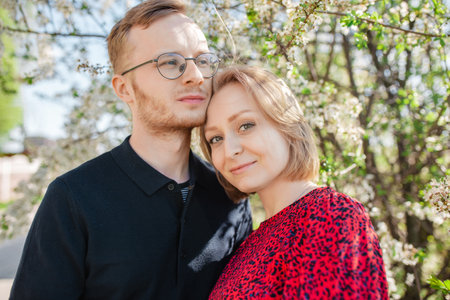 A portrait of a joyful young couple embracing amidst a stunning blossoming tree. Expressing the themes of love, unity with nature, and the beauty of springの写真素材