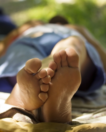 foot and a heel of the young man laying on a grassの写真素材