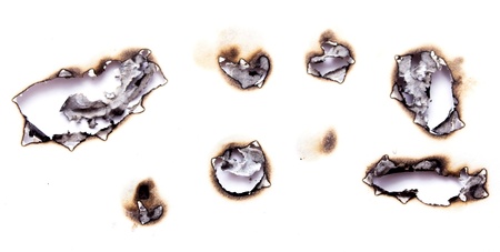 Collection of burnt holes in a piece of paper isolated on white backgroundの写真素材