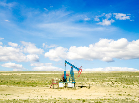 pumping oil from an oil well on the background of sky with cloudsの写真素材