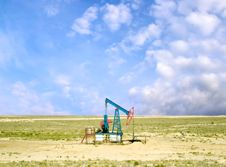 pumping oil from an oil well on the background of sky with cloudsの写真素材