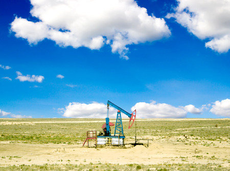 pumping oil from an oil well on the background of sky with cloudsの写真素材