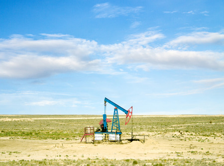 pumping oil from an oil well on the background of sky with cloudsの写真素材