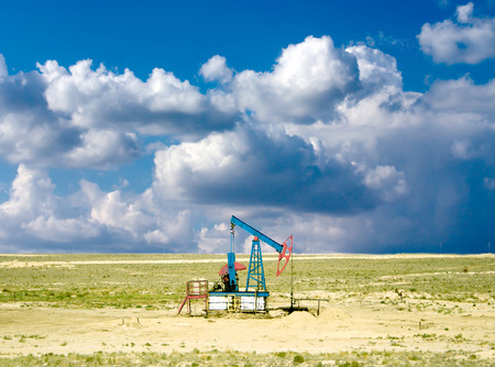 pumping oil from an oil well on the background of sky with cloudsの写真素材