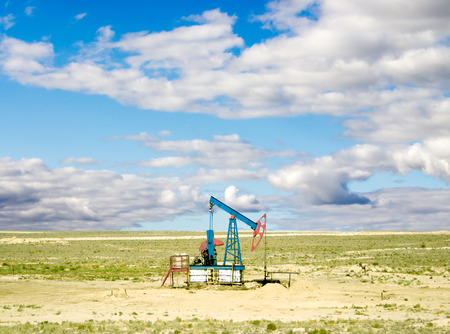pumping oil from an oil well on the background of sky with cloudsの写真素材