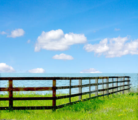 wooden fence on the river on a background of blue sky with cloudsの写真素材
