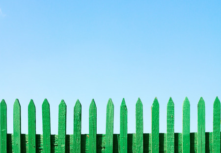 green wooden fence on a blue sky backgroundの写真素材