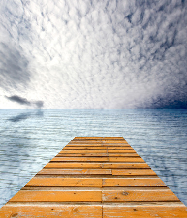wooden pier on sunny day with white clouds and sunの写真素材