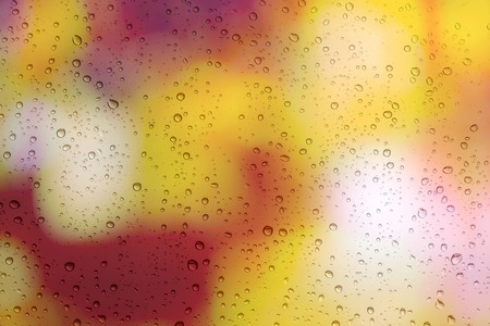 Drops of rain on window with bokeh lights backgroundの写真素材