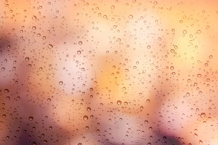 Drops of rain on window with bokeh lights background
