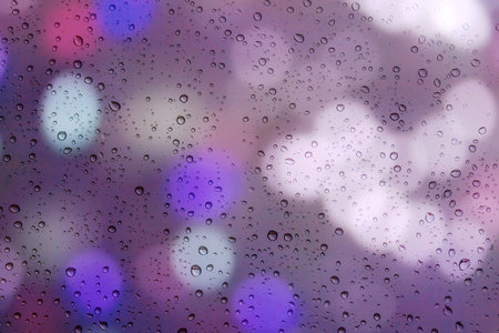 Drops of rain on window with bokeh lights background