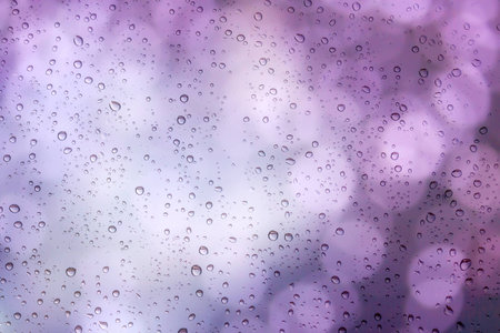 Drops of rain on window with bokeh lights background