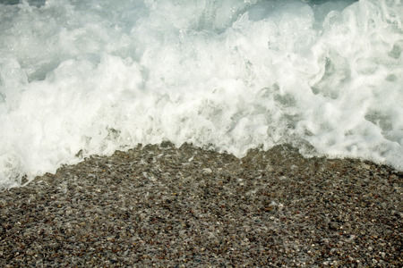 Sea wave foam on the pebble beach.の写真素材