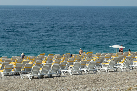 loungers  umbrellas standing in a row under the bright sun  along the coastlineの写真素材