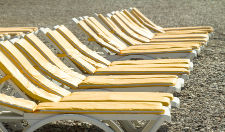 loungers  umbrellas standing in a row under the bright sun  along the coastlineの写真素材