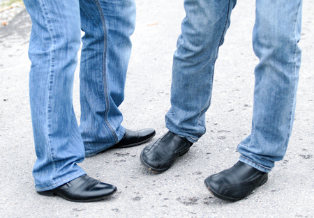 Man's feet in blue jeans in shoes close up, set in motion