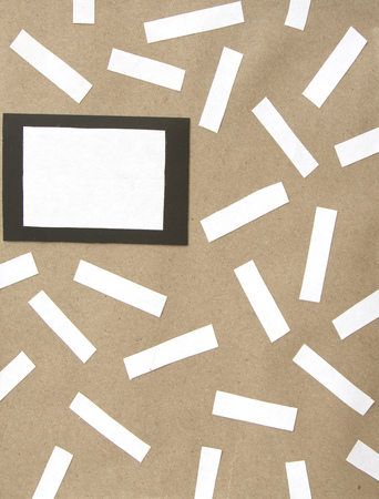 Pieces of white note paper black square on brown background