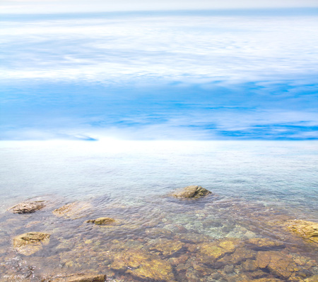 rocky entrance to the sea on a background of blue sky with cloudsの写真素材