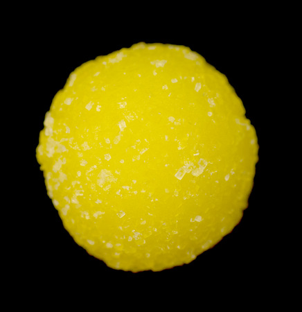 round yellow sugar candy on a black background
