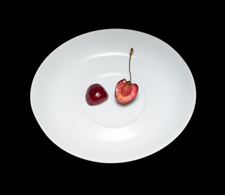 Cherry on a white plate, black backgroundの写真素材