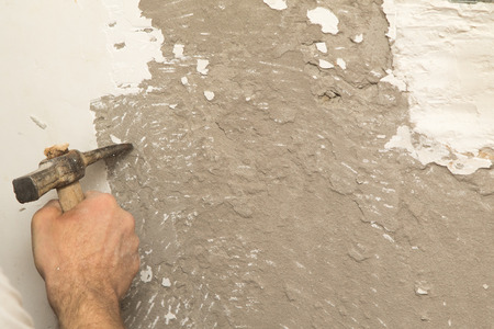work with a hammer on the wall of the plasterの写真素材
