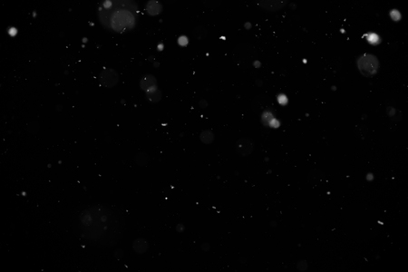 Snowstorm texture. Bokeh lights on black background, shot of flying snowflakes in the airの写真素材