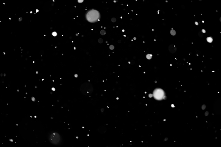 Snowstorm texture. Bokeh lights on black background, shot of flying snowflakes in the airの写真素材