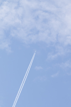 high in the sky a white plane fliesの写真素材